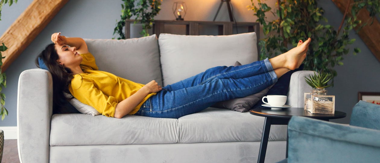 Woman relaxing on the couch at home with a cup of tea