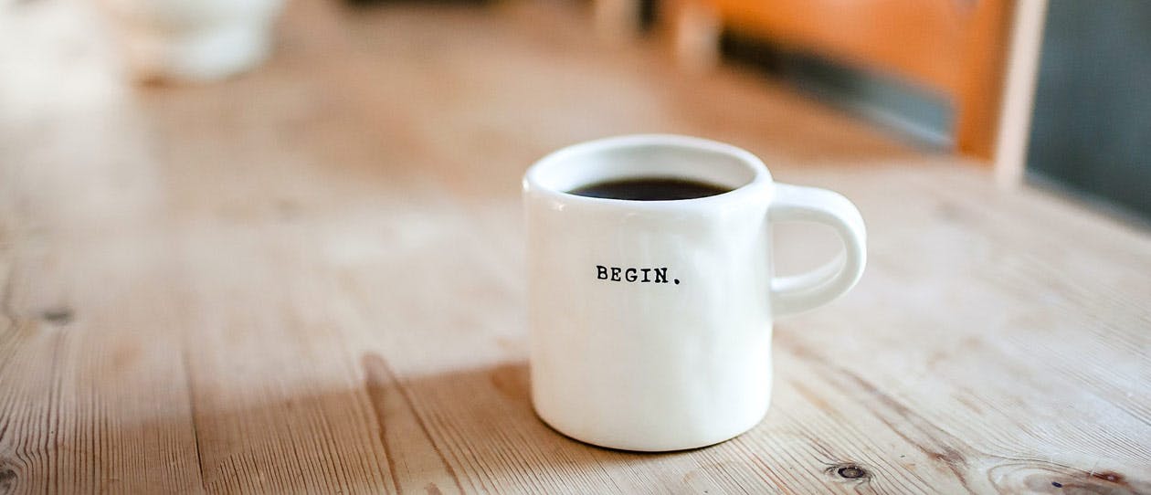 White coffee mug with the word 'Begin' on a wooden table