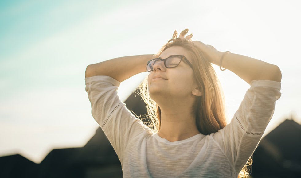 Woman holding her face up into the sun with her eyes closed