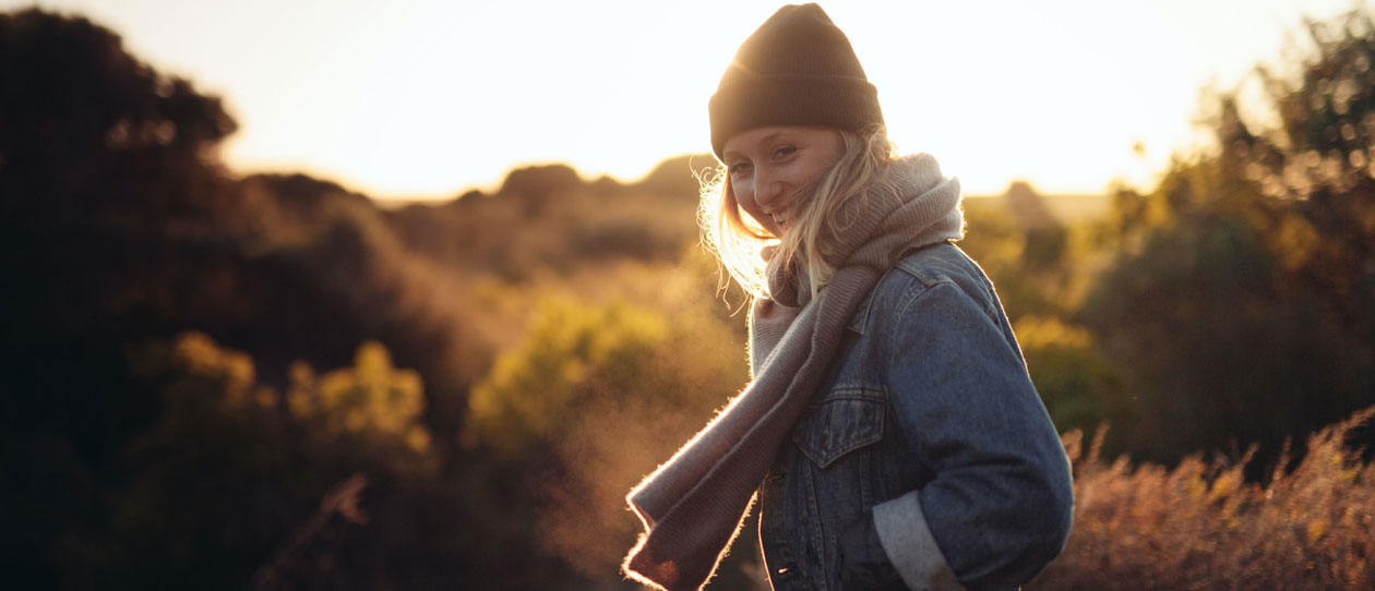 Young woman standing in a field outside at sunrise in cold weather
