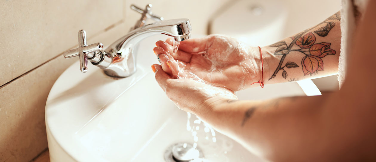 Woman washing her hands at the bathroom sink with soap and water