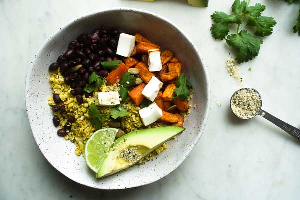 Mexican cauliflower rice in a bowl with sweet potato, lime and avocado