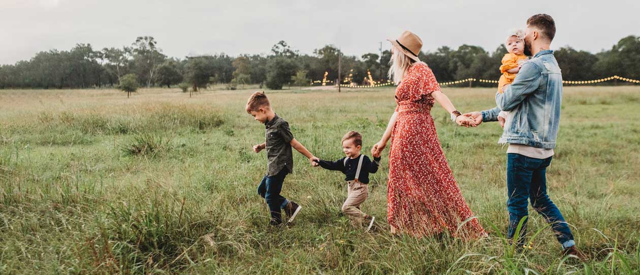 Young family of five walking through a grassy field