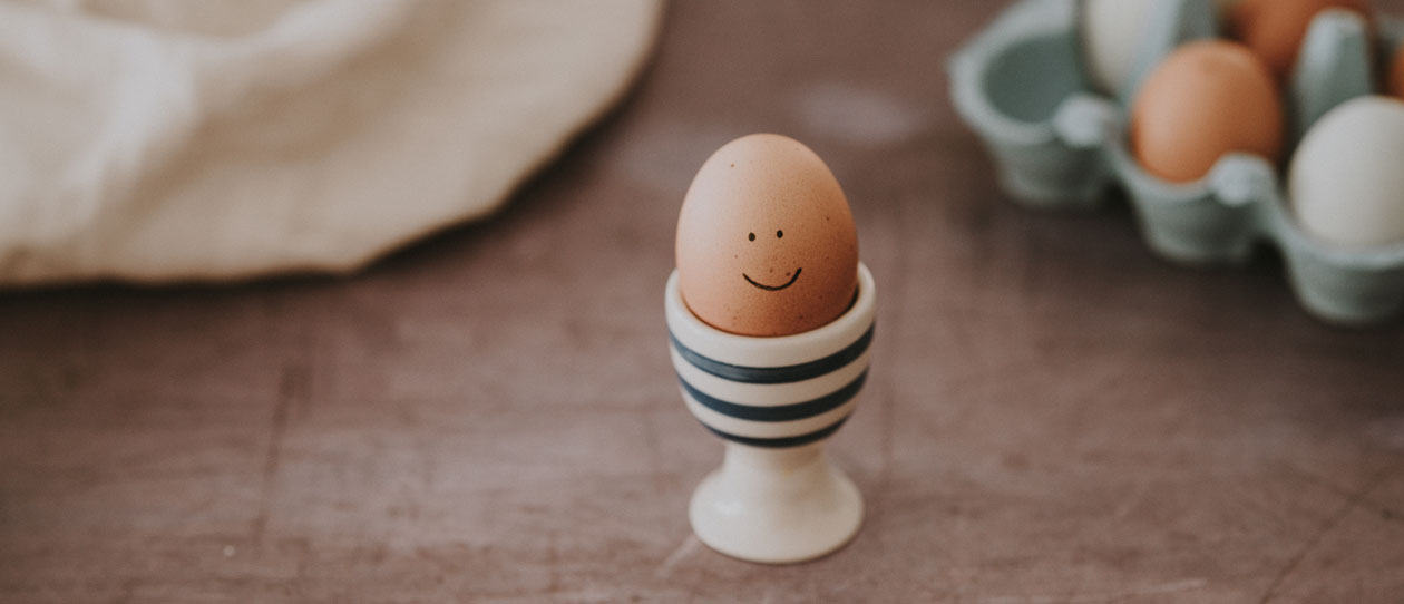 Boiled egg with a smiley face in a striped egg cup