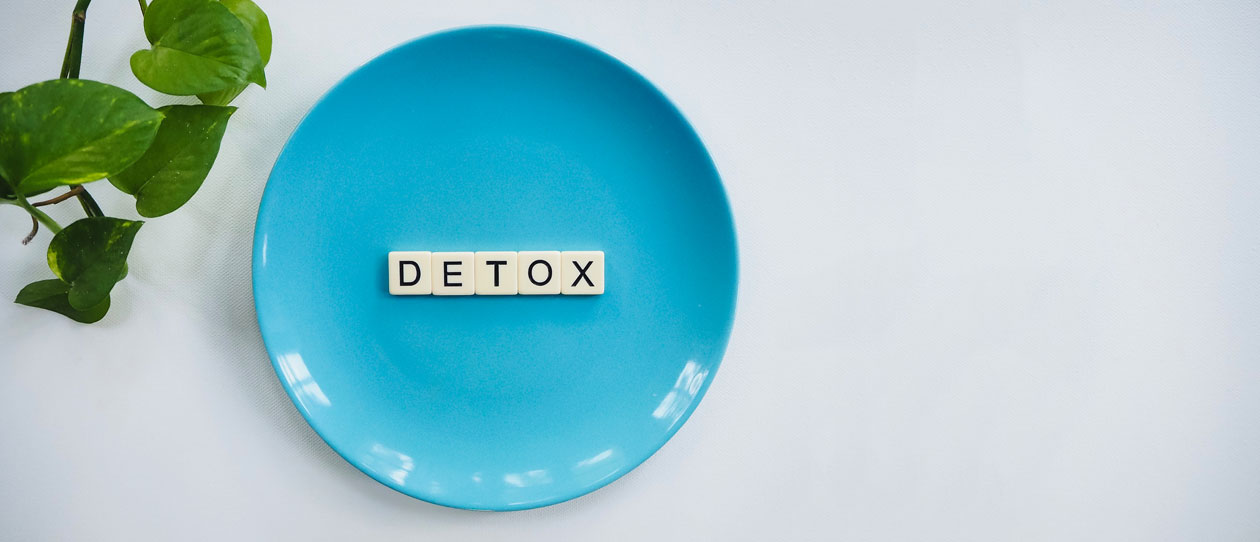 Blue plate on a white background with scrabble letters spelling detox