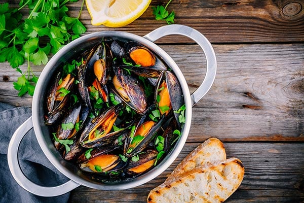 Mussels in a pan with parsley, lemon and crunchy bread