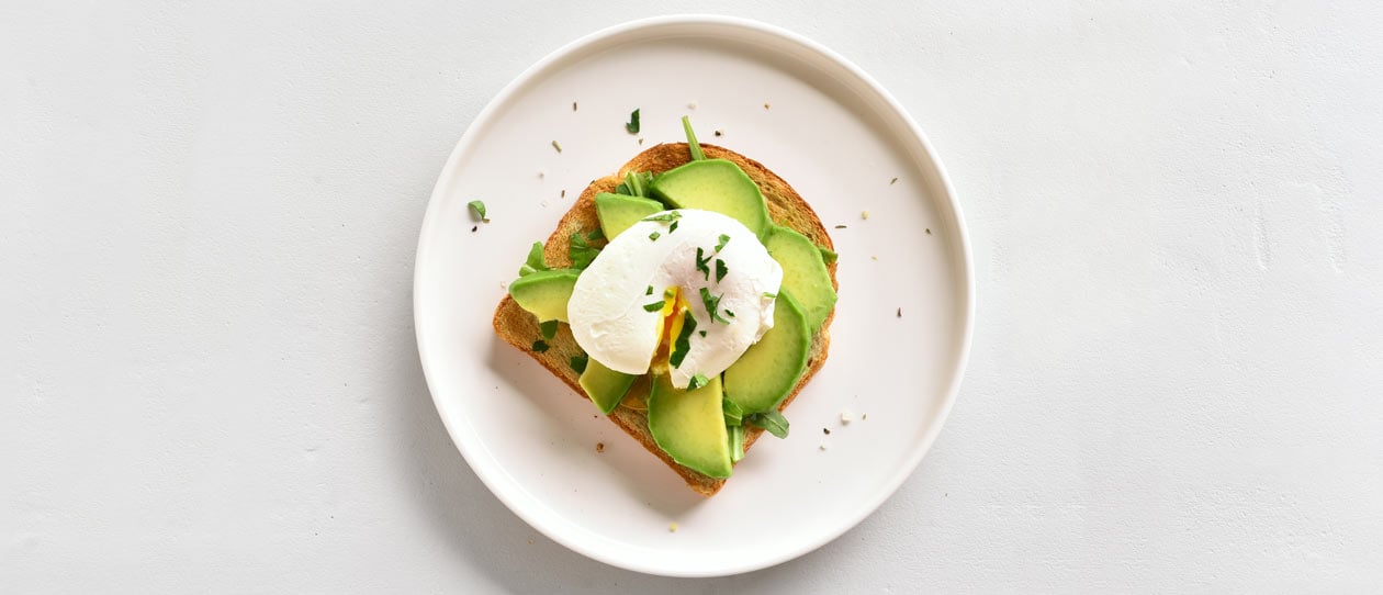 Avocado and egg on toast on a white plate