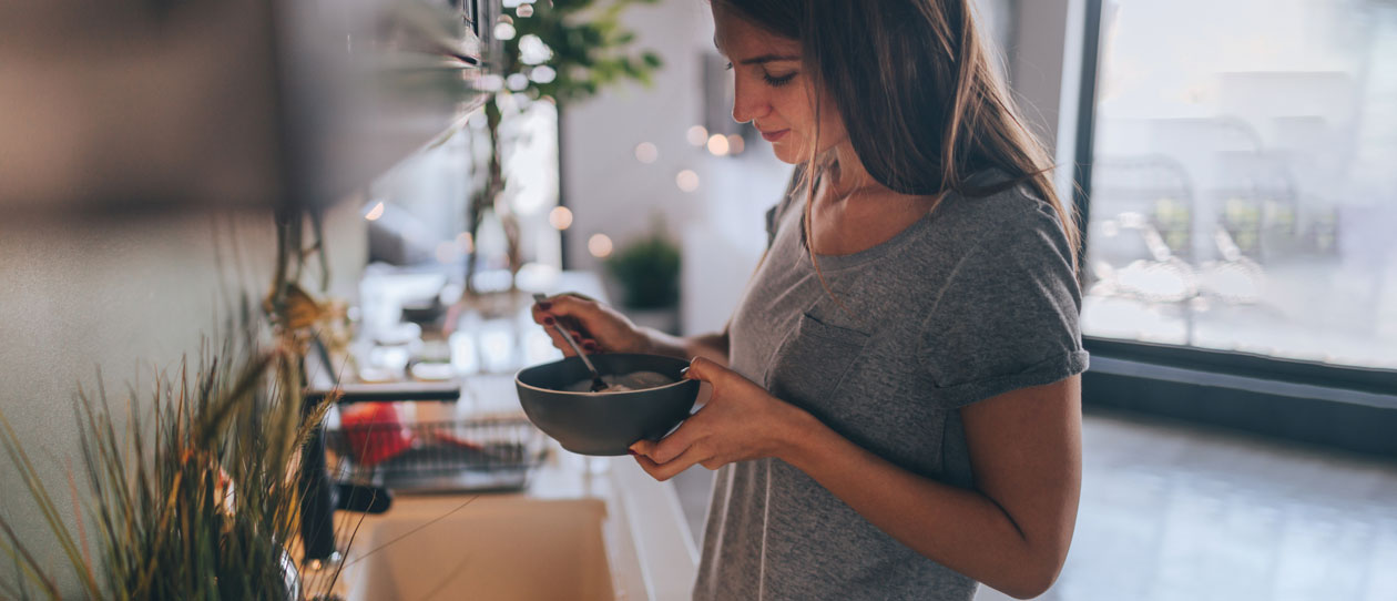 Woman eating a bowl of cereal for breakfast in the kitchen