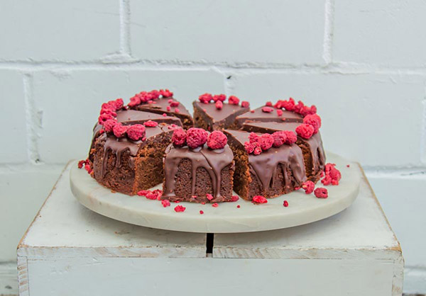 Vegan chocolate cake with raspberries, sliced on a white plate