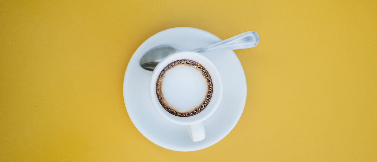 Flat lay of a cup of coffee on a yellow background