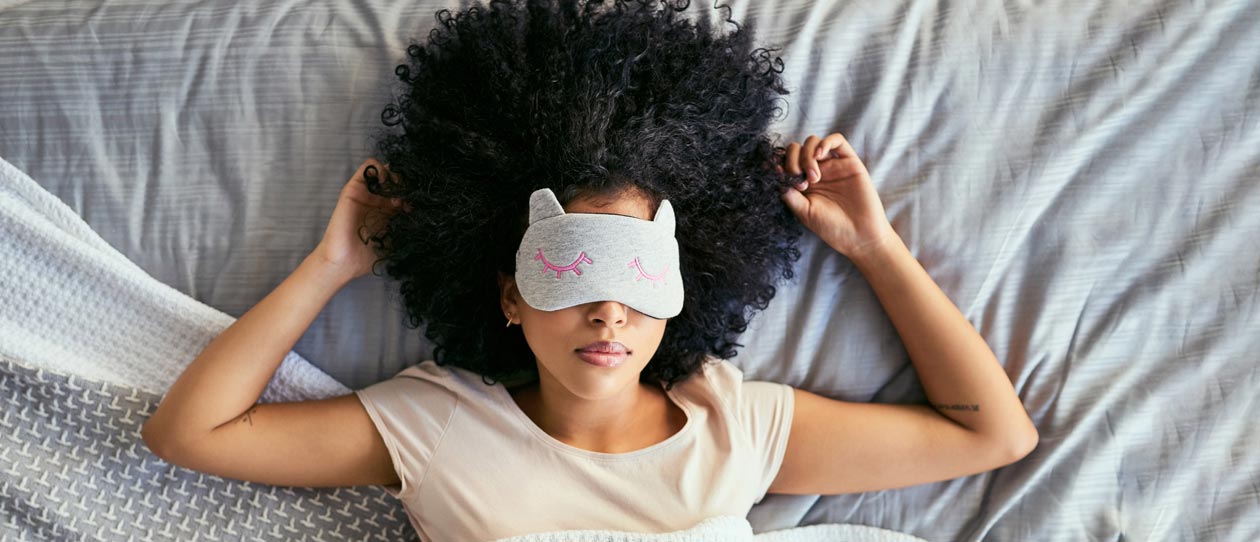 Woman sleeping in a bed wearing an eye mask