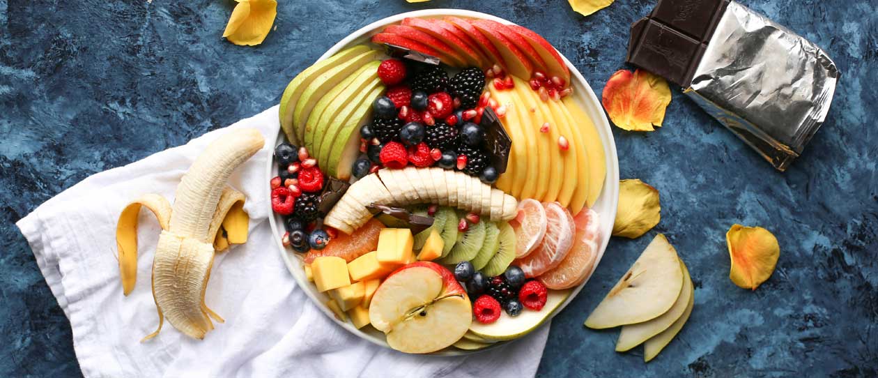 Chopped fruits in a white bowl on a blue surface
