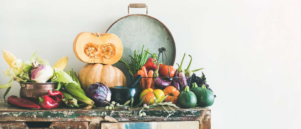 Assortment of various high fibre vegetables for healthy cooking over wooden rustic cupboard, white wall background, copy space. Local market organic produce