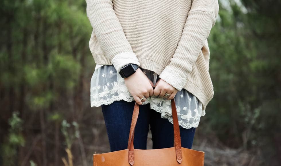 Woman standing in the forest holding handbag
