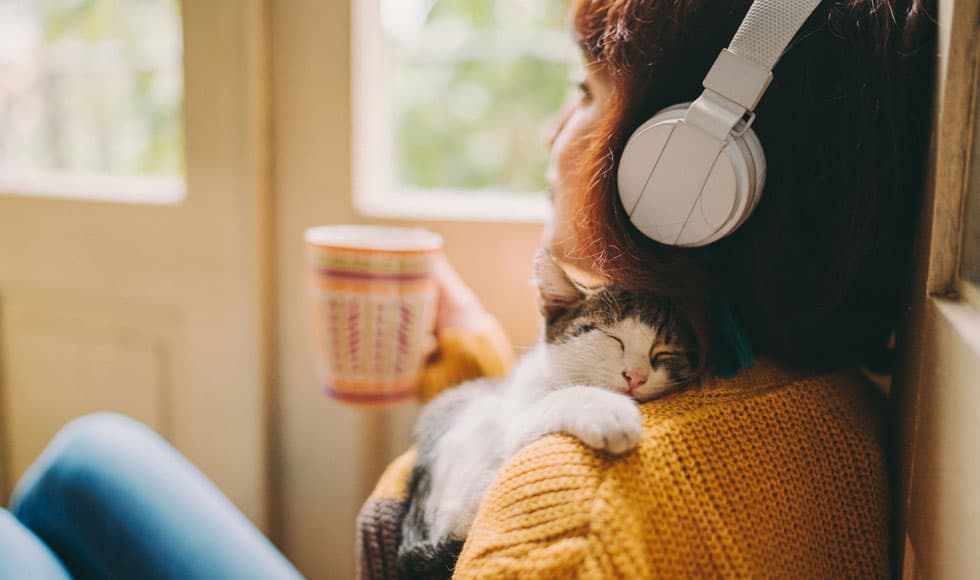 Woman relaxing at home with a cup of tea and her kitten
