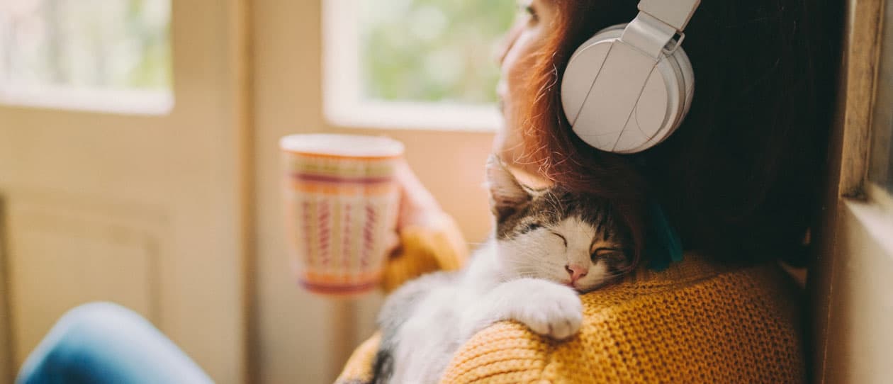 Woman relaxing at home with a cup of tea and her kitten