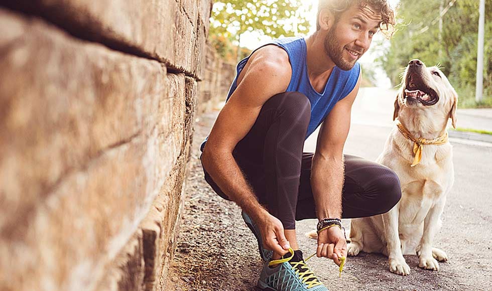 man tying his shoelaces ready to run with labrador