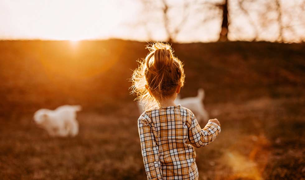 Little girl running around outside with her dogs