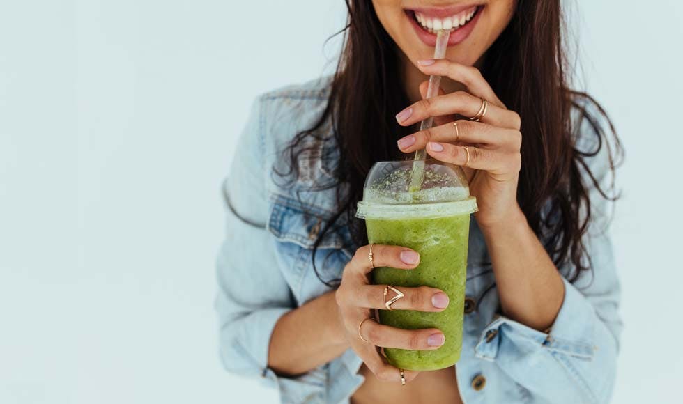 Healthy young woman drinking a green juice