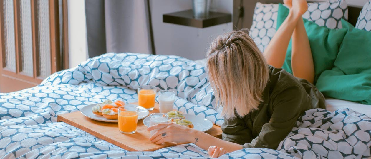 Woman lying on the bed next to a breakfast tray