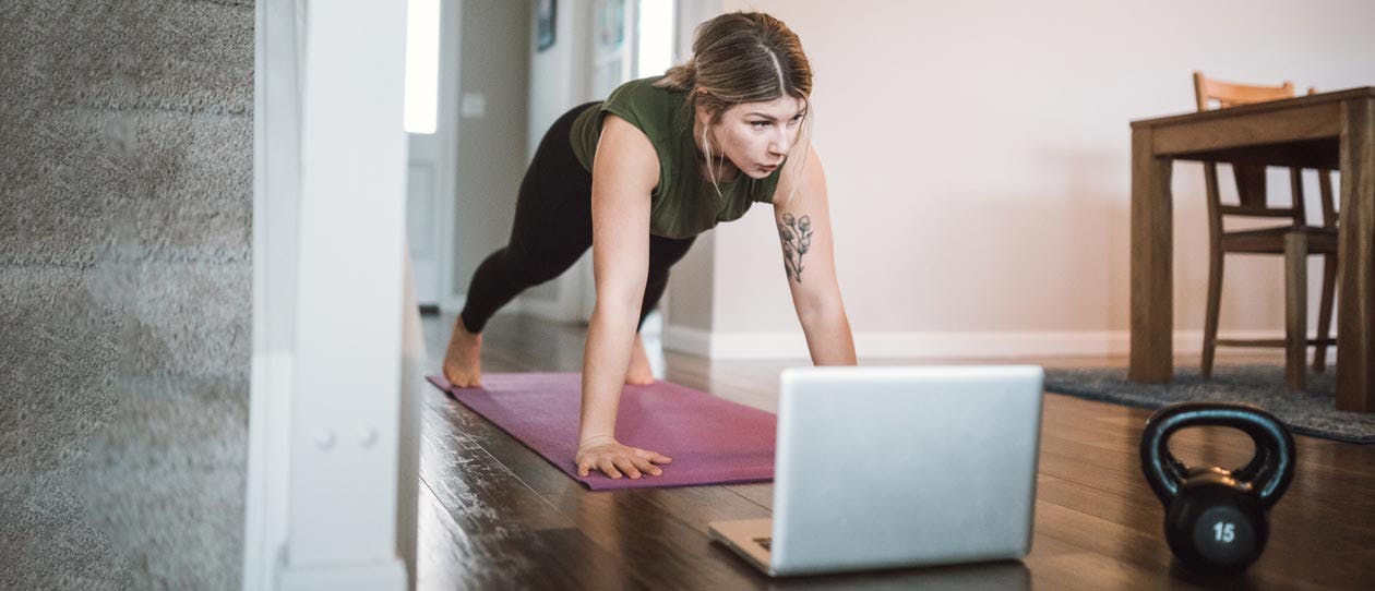 Young woman in the plank position working out from home