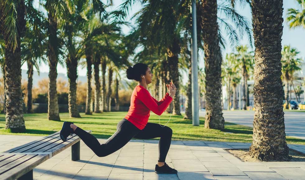 Woman doing a lunge on a park bench