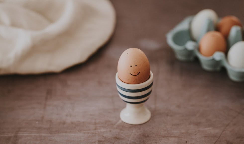 Boiled egg with a smiley face in a striped egg cup 