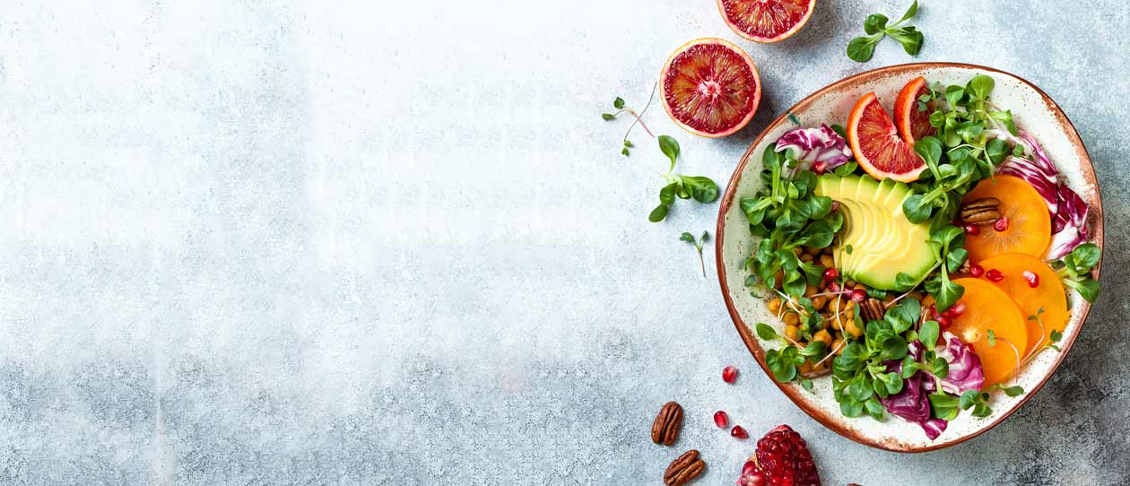 Vegan, detox Buddha bowl with turmeric roasted chickpeas, greens, avocado, persimmon, blood orange, nuts and pomegranate.