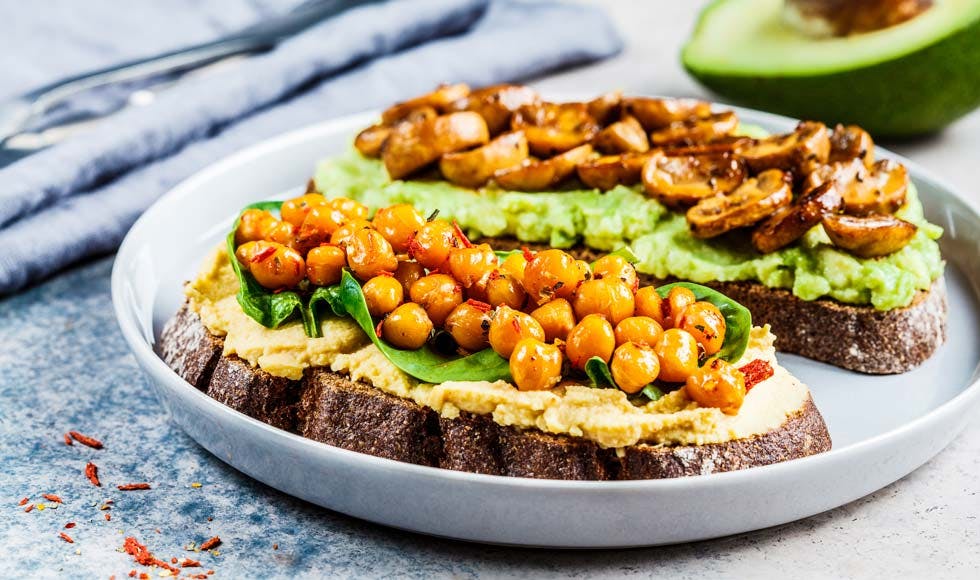 Vegan toasts with hummus and chickpeas, guacamole and mushrooms on rye bread.