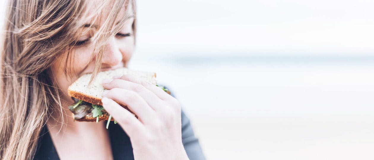 Up close image of a young woman eating a sandwich
