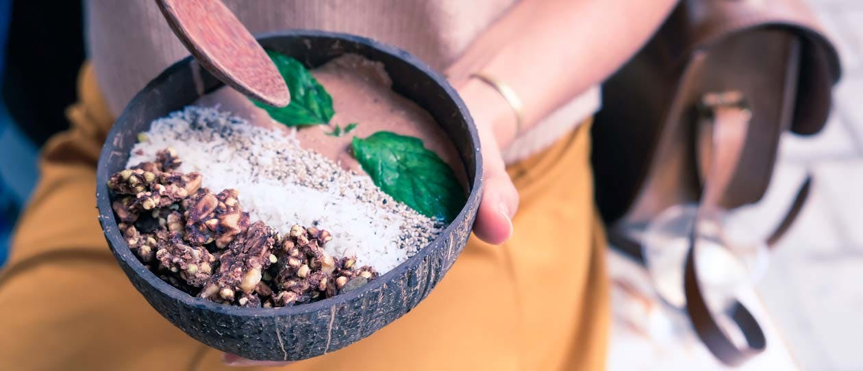 Woman holding a banana and cacao smoothie bowl