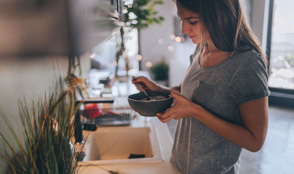 Woman eating a bowl of cereal for breakfast in the kitchen