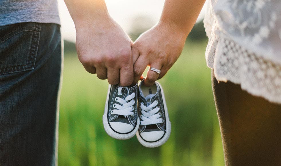 Man and woman holding baby high top sneakers