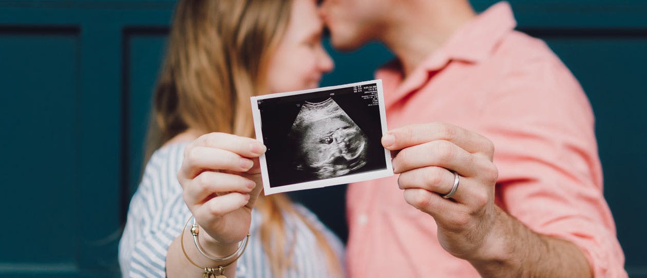 Man and woman holding up ultrasound image