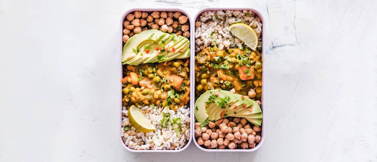 Two lunch boxes side by side with rice, lentils and chickpeas