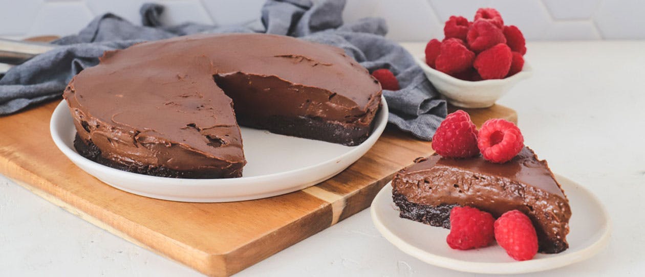 Chocolate avocado and almond mousse cake with fresh raspberries on a white plate