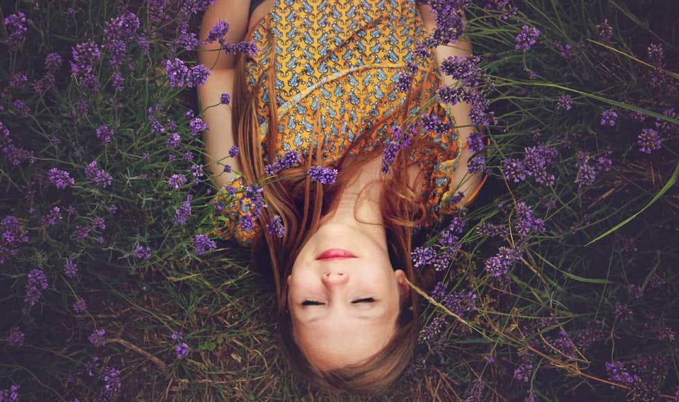 Young woman lying on the ground on a field of purple flowers