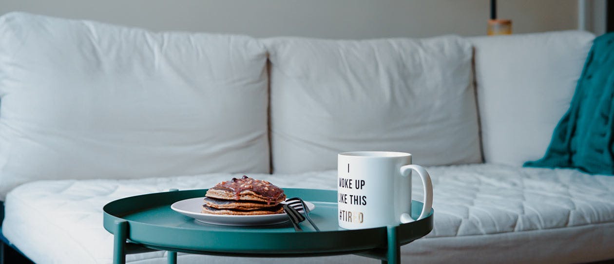 Pancakes and coffee on a side table infront of a sofa bed