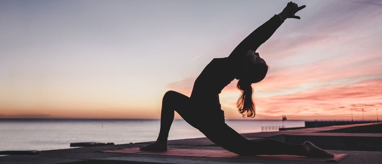 Silhouette of woman doing yoga at sunrise 