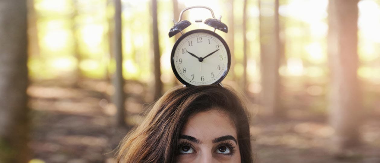 Woman looking up at a clock on her head