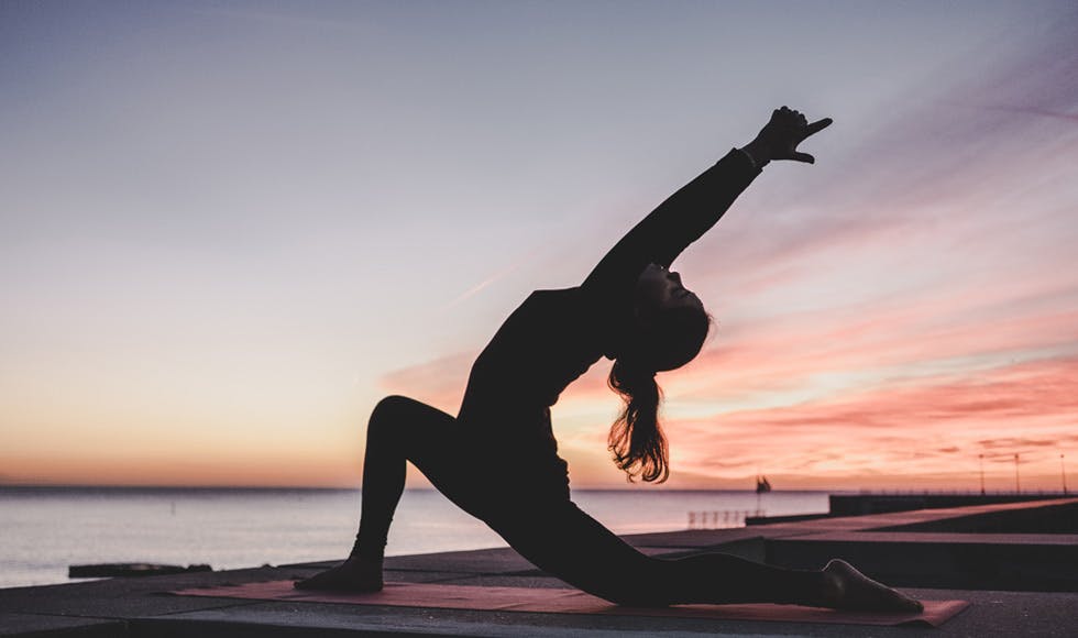 Silhouette of woman doing yoga at sunrise 